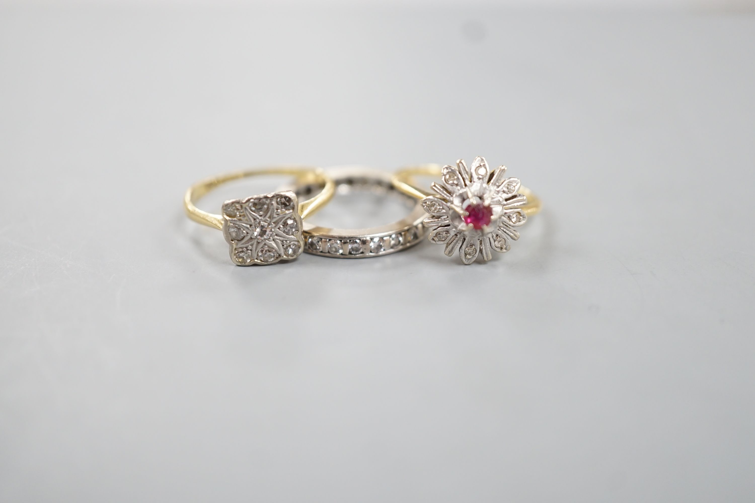 A white metal an diamond chip set full eternity ring, size J/K, gross 3.4 grams, a 1920's 18ct and nine stone diamond set tablet ring, size K/L, gross 2.4 grams and a yellow metal and gem set cluster ring, gross 3 grams.